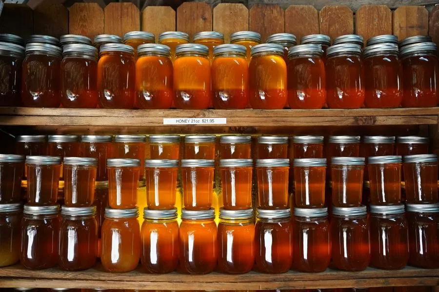 Rows of honey jars on wooden shelves